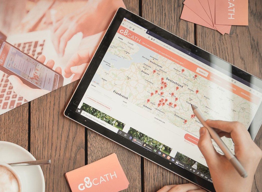 Ein Tablet auf dem die Gocath Webseite zu sehen ist und eine Hand mit Stift die etwas zeigt