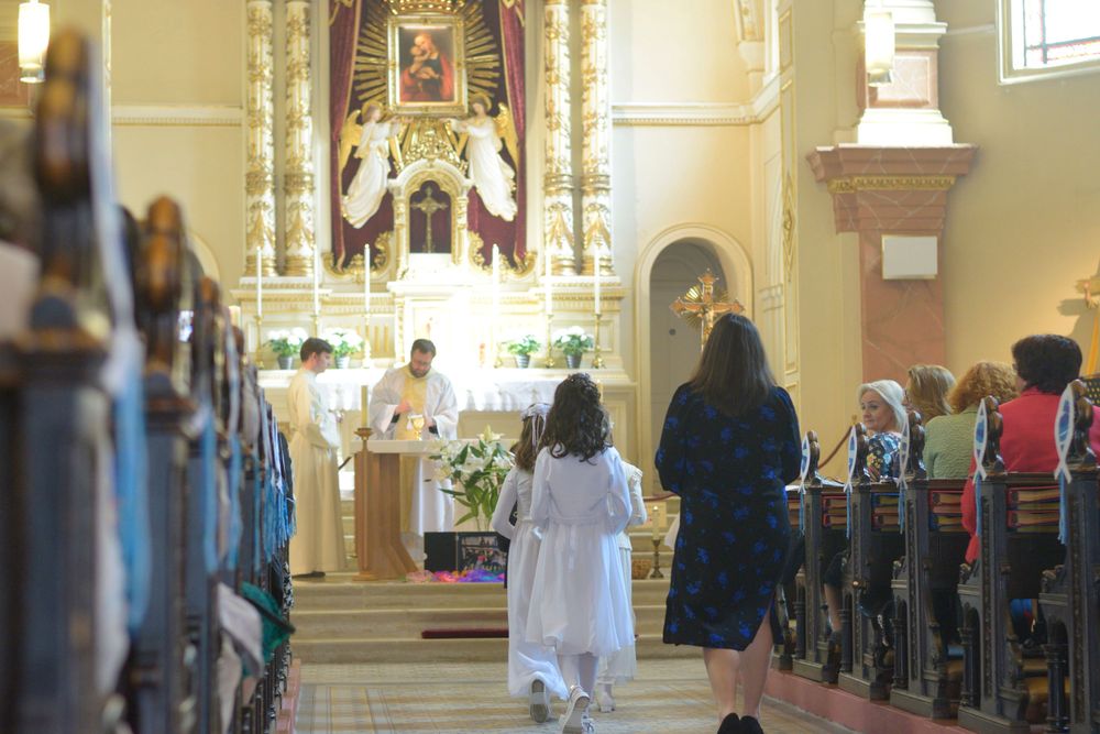 Mädchen in weißen Kleidern laufen zum Altar bei der Erstkommunion