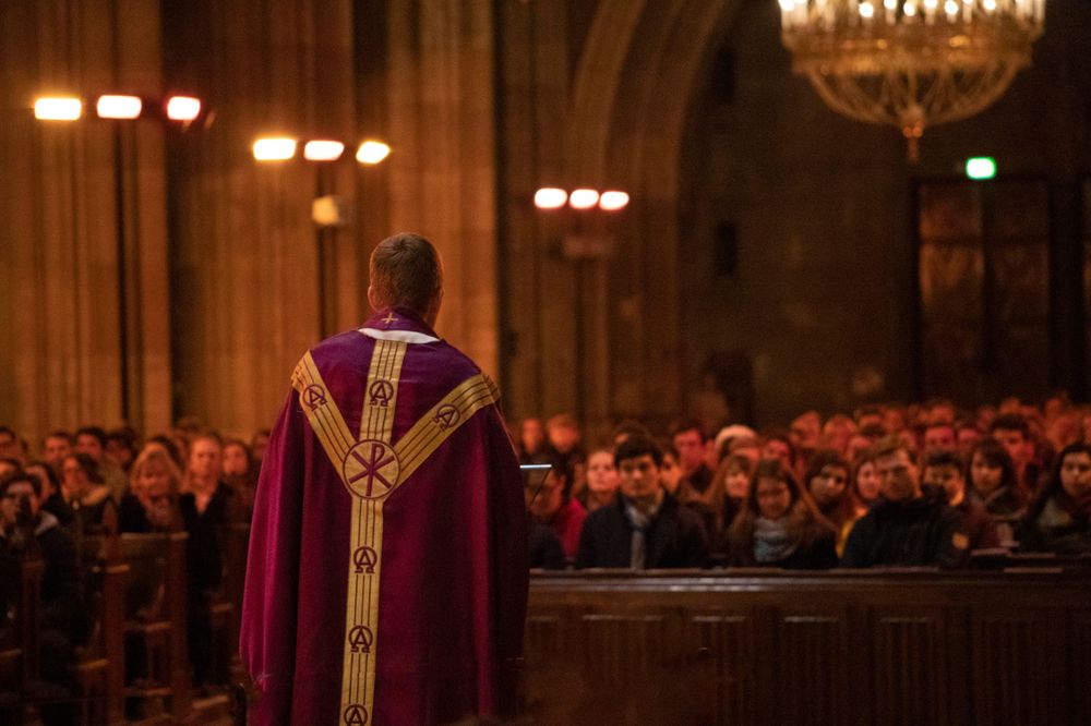 Studentenmesse in Wien, volle Kirche in Wien; Priester predigt in Studentenmesse zu jungen Studenten in Wien, die Kirchenbänke sind voll