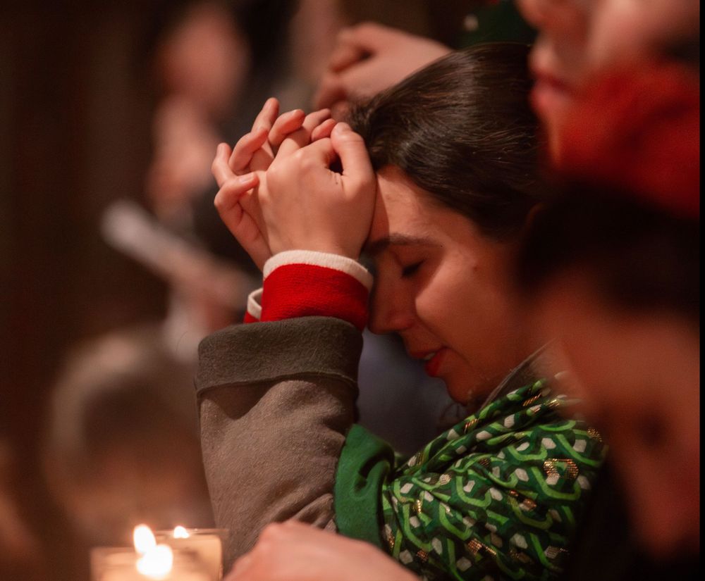junge Frau betet, warmes Kerzenlicht kommt von unten
