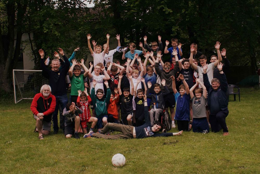 Eine Gruppe von Jungs beim Fußballspielen. Sie strecken die Arme in die Luft und haben eine gute Zeit und coole Gemeinschaft